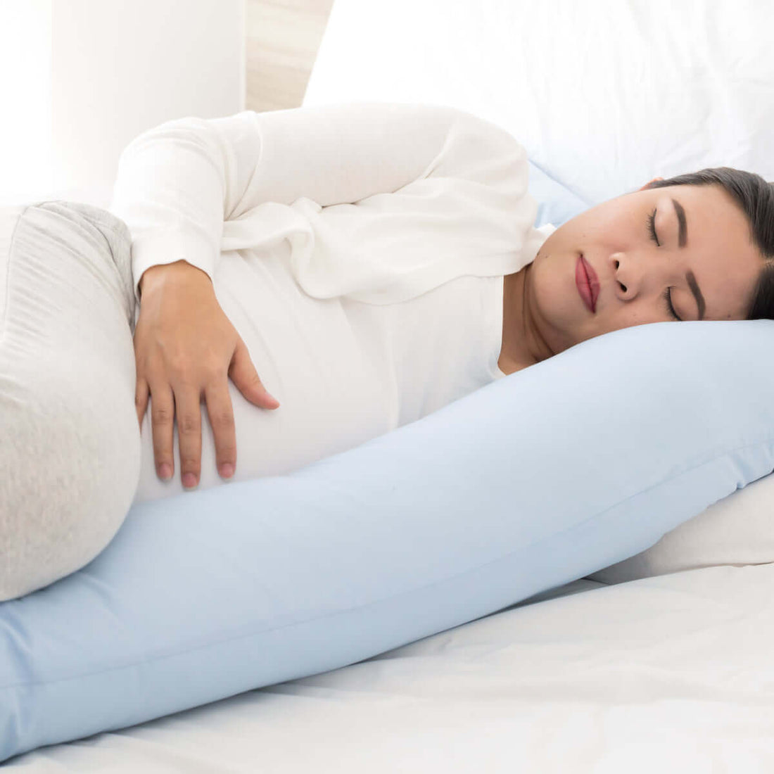 Woman lying down supported by a body pillow in a blue pillowcase